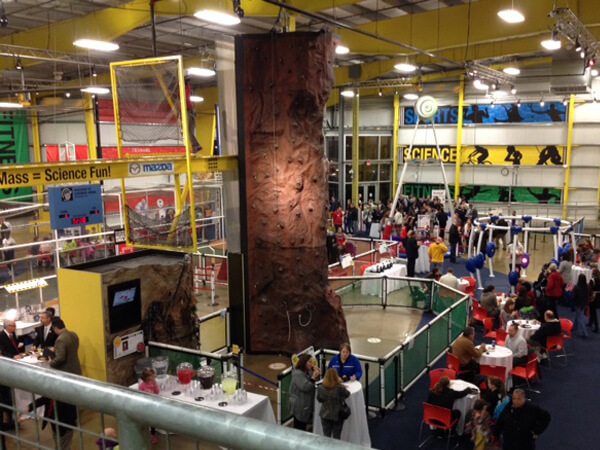 Large room with rock wall in the center surrounded by tables and chairs.