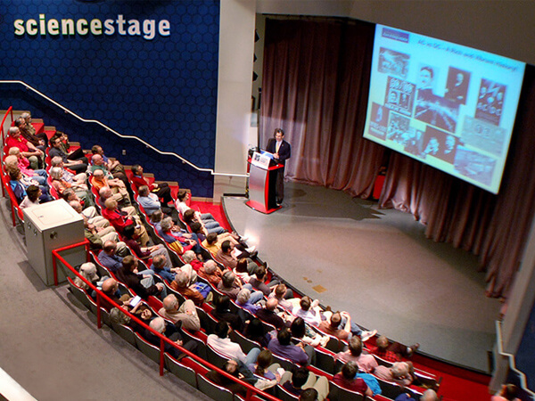 Auditorium and stage with a man giving a presentation.