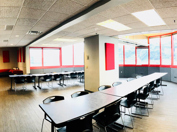 Room filled long white tables with black chairs.