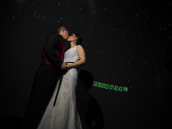 Newlywed couple kissing inside portable planetarium