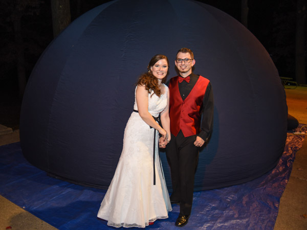 Newlywed couple standing in front of portable planetarium