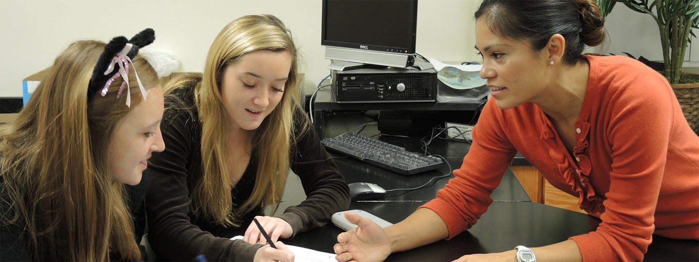 Two high school girls talking to teacher