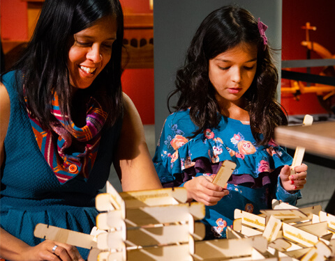 Mother and daughter buiding with interloclocking pieces of wood.