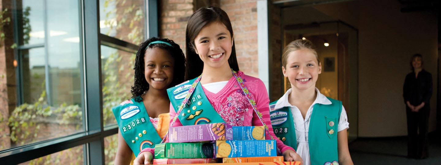 Girl scouts smiling holding boxes of cookies