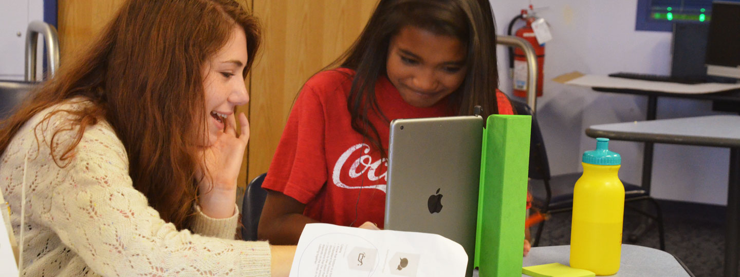 Two girls looking at iPad and smiling