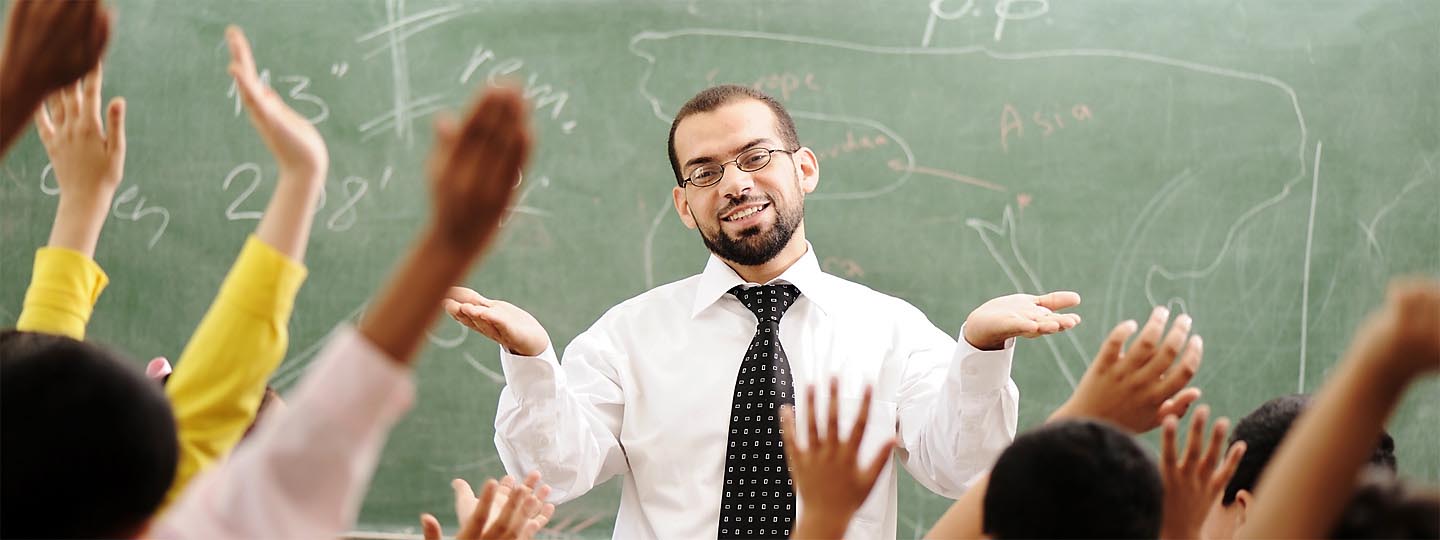 Teacher at front of class with students raising hands