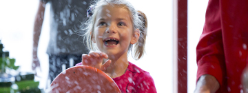 Young girl spins the wheel to make it rain at H2Oh’s water table.