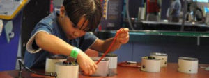 A child connecting a wire from one area to another at the Exploration Station